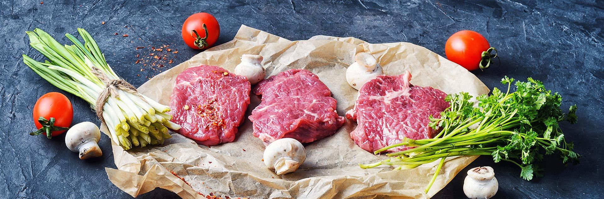 Zartes Stück Kalbfleisch mit Kräutern und Gewürzen auf dunklem Untergrund