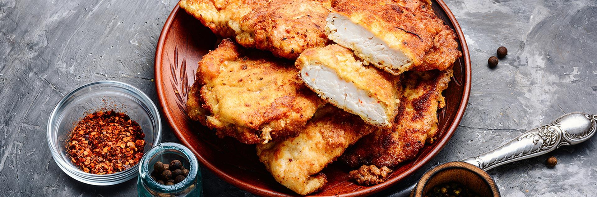 Putenschnitzel angerichtet auf einem Teller neben Gewürzen