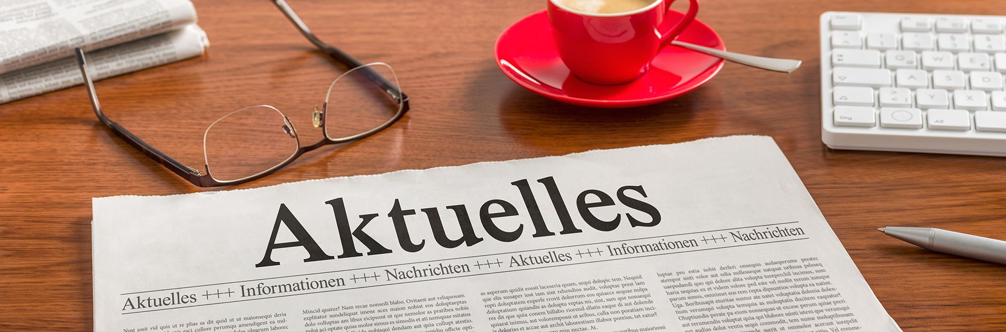 Zeitung und Brille auf einem Schreibtisch