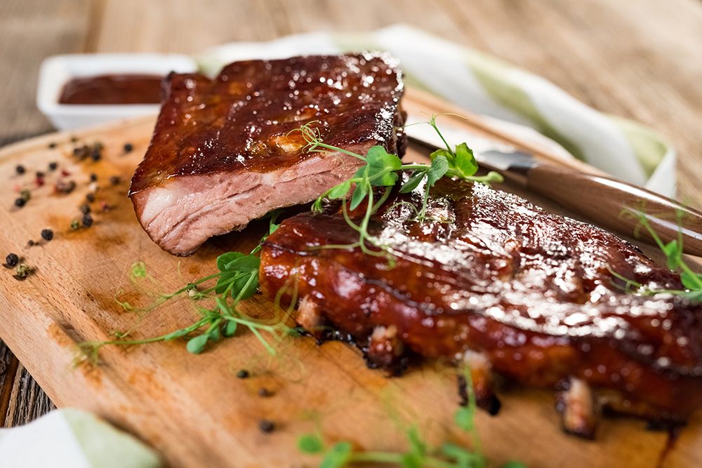 Spareribs überstrichen mit BBQ Sauce auf Holzbrett