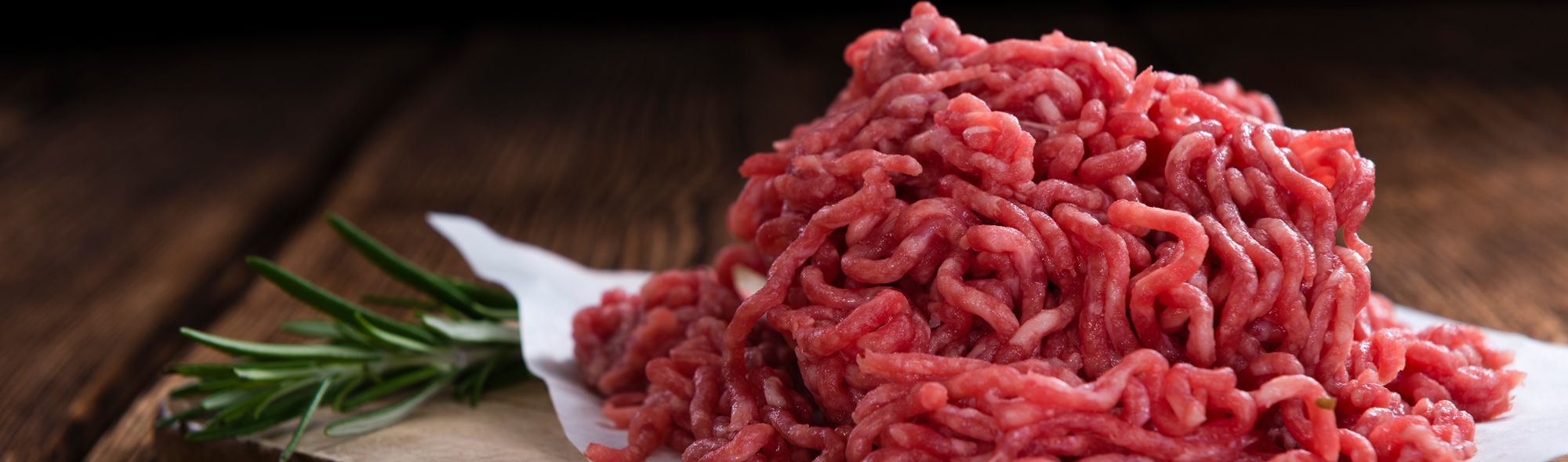 Frisch gewolftes Hackfleisch mit Kräutern und Gewürzen auf dunklem Untergrund